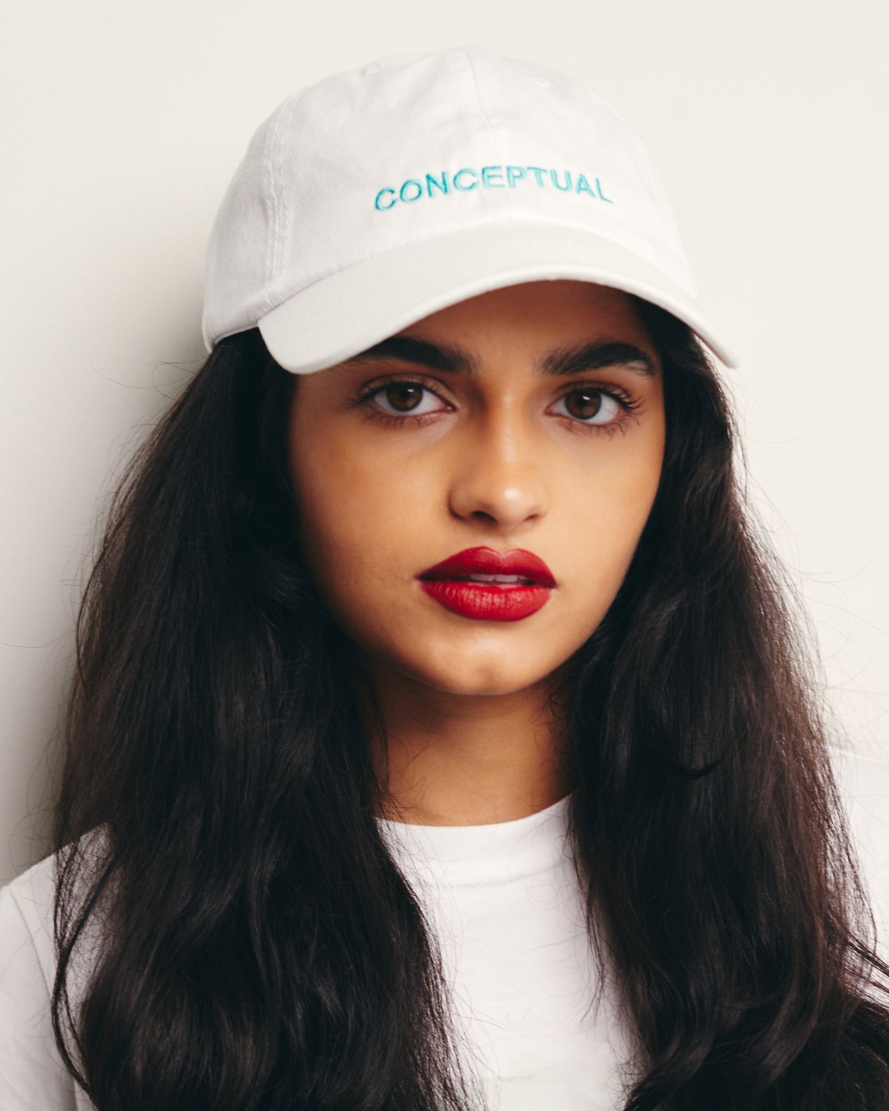 Mira Bhat wears White Baseball Cap / Dad Hat with Conceptual Art Movement Text Embroidery on Front. 100% Cotton.